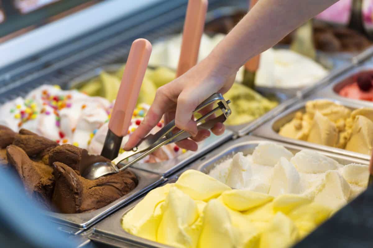 Interior of an ice cream counter with a saleswoman preparing a chocolate flavored tub